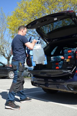 Tekniker lastar in sin fällbara aluminiumkärra i bilen